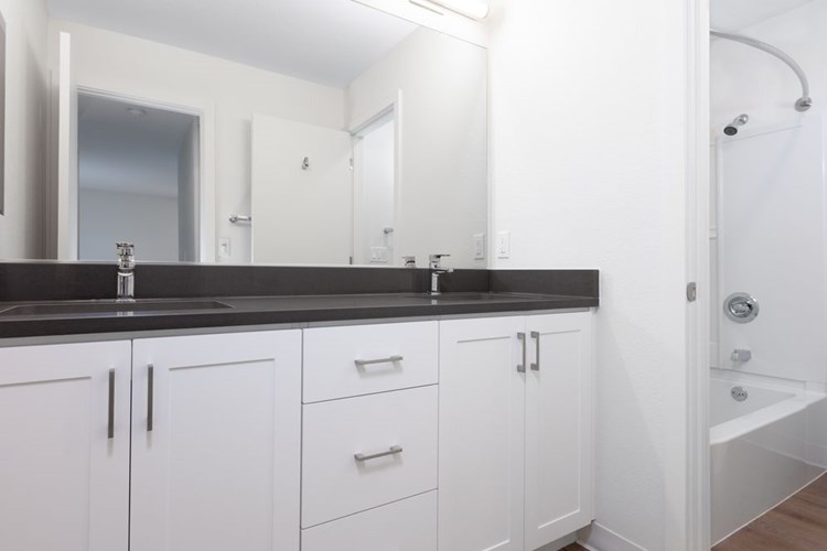 Bathroom with double vanity, grey countertop, white cabinetry and hard surface flooring