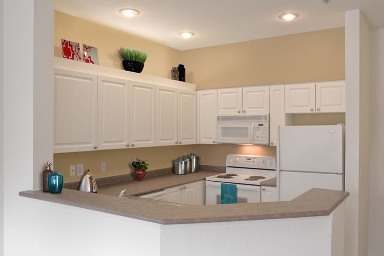 Classic Package I kitchen with white appliances, laminate countertops, white cabinetry, and laminate or hard surface flooring