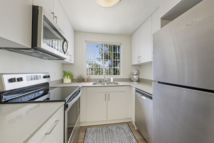 Renovated I kitchen with white cabinetry, grey quartz countertops, stainless steel appliances, upgraded lighting and fixtures, and hard surface flooring throughout the home