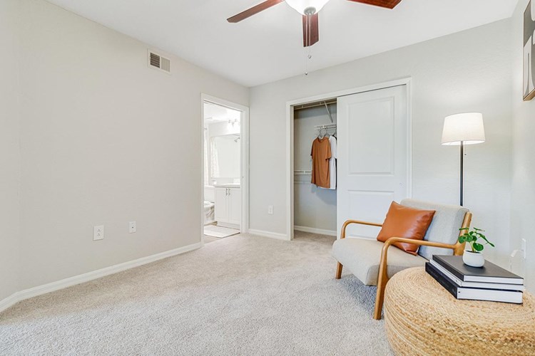 Spacious, open, master bedroom with plush carpeting, a ceiling fan, spacious closet, and a private bathroom.