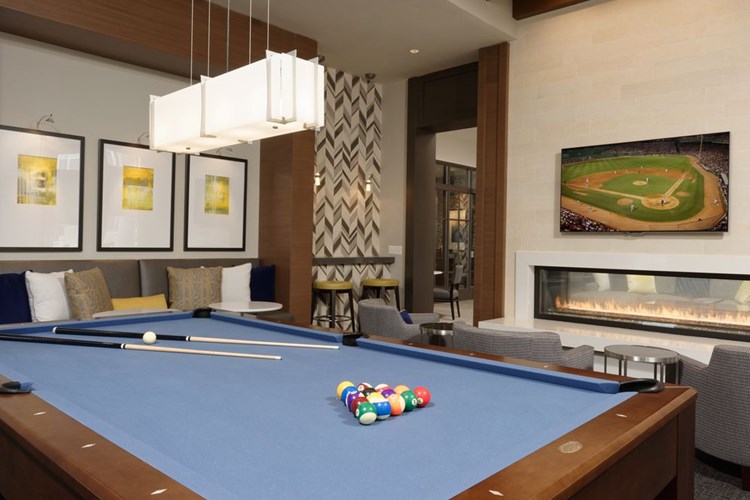 Resident lounge and game room with billiards and fireplace with seating