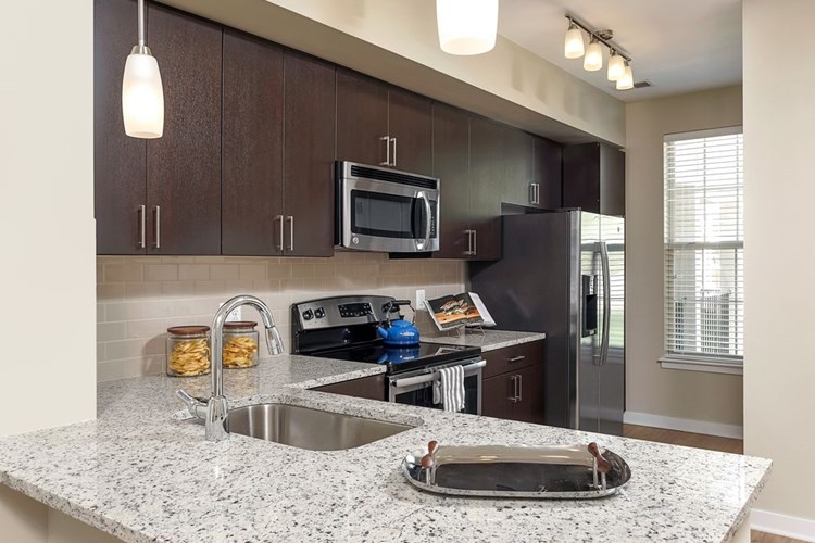 Kitchen with granite countertop, espresso cabinetry, stainless-steel appliances and hard surface flooring