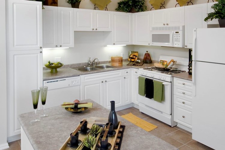 Classic Package I kitchen with island featuring white cabinetry, white appliances, laminate countertops, and tile flooring