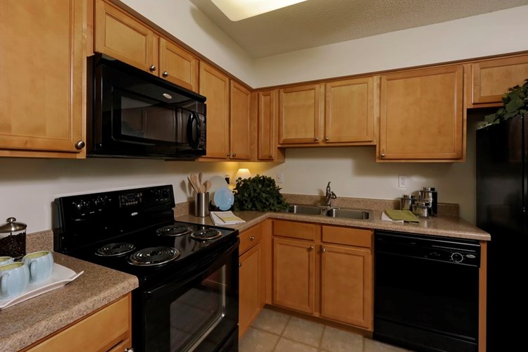 Finish Package II kitchen with oak cabinetry, beige laminate countertops, black appliances and tile flooring