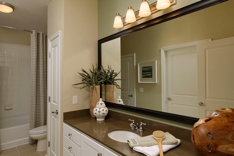 Bathroom with quartz stone countertop, white cabinetry and linen closet
