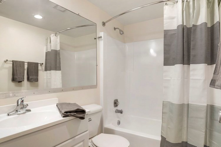Renovated Package II bath featuring white cabinetry and countertops