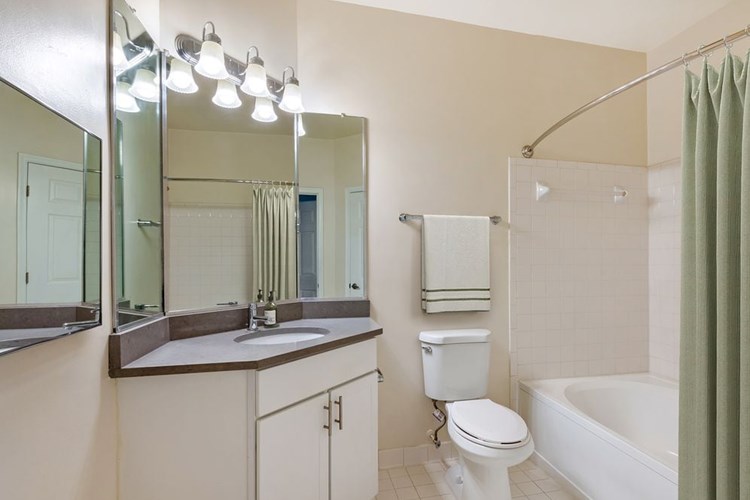 Renovated Package I bath with white cabinetry, grey quartz countertops, and hard surface flooring