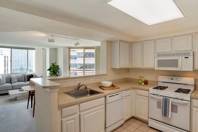 Classic Package I kitchen with white cabinetry, beige granite countertops, white appliances, and carpet