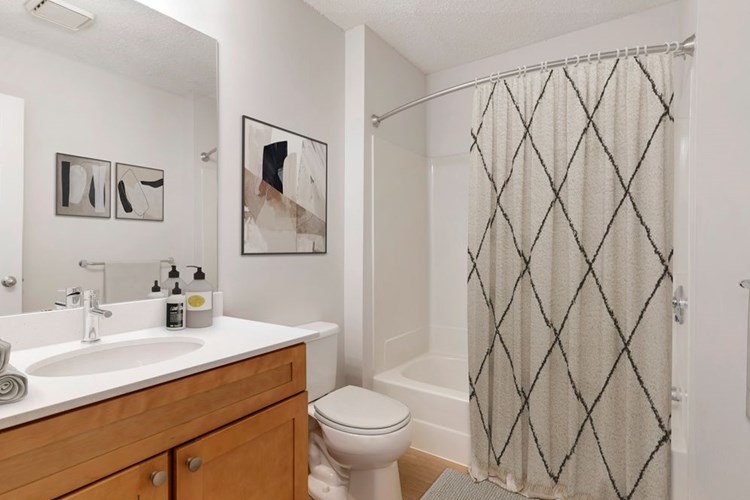 Renovated Package I bath with white quartz countertops, maple cabinetry, and hard surface flooring