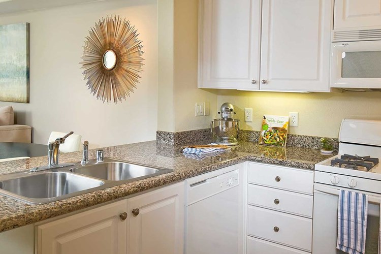 Classic Package I kitchen with white appliances, beige speckled granite countertop, white cabinetry, and hard surface flooring