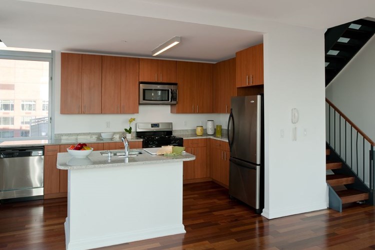 Penthouse South kitchen with stainless steel appliances, cherry cabinetry and grey granite countertops