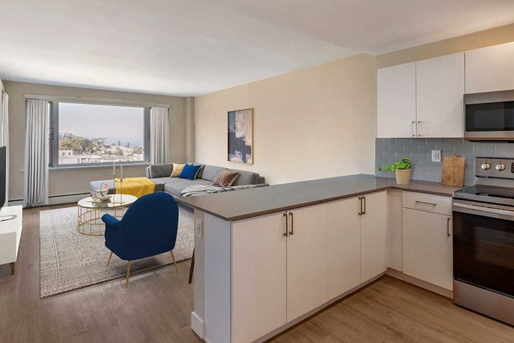 Limited availability: newly renovated Finish Package II apartment homes featuring kitchens with grey quartz countertops, white cabinetry, stainless steel appliances, grey tile backsplash, and hard surface flooring