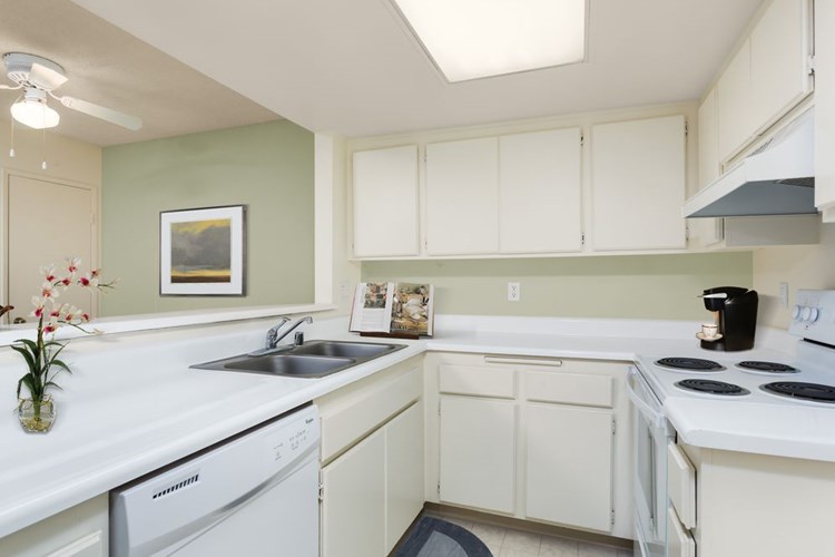 Classic Package kitchen with white appliances, white laminate countertops, white cabinetry, and vinyl flooring