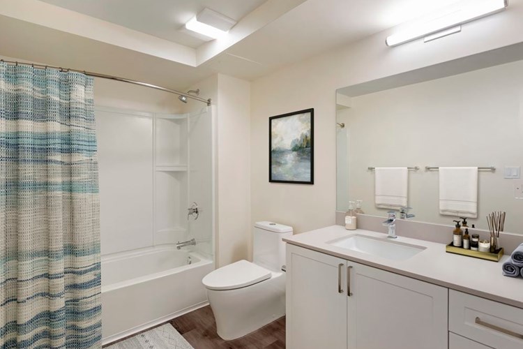 Bath with beige quartz countertops, white cabinetry, and hard surface flooring (Select Home)