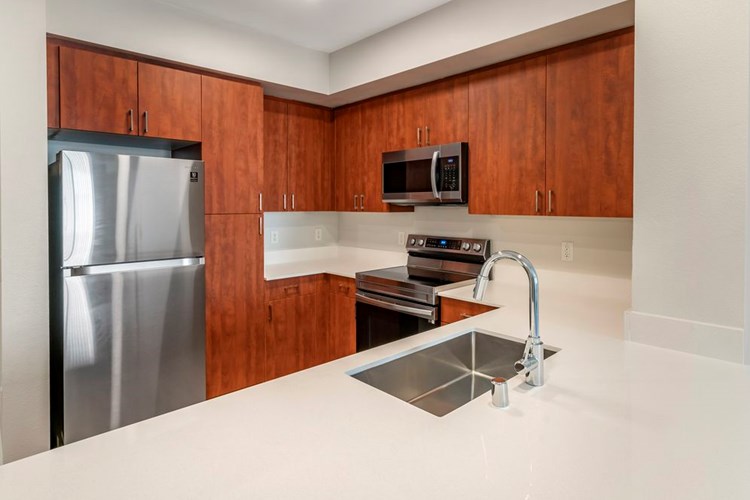 Renovated Package I kitchen with maple cabinetry, white quartz countertops, stainless steel appliances, and hard surface flooring