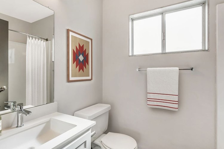 Renovated Package I bath with white quartz countertops, white cabinetry, and hard surface flooring
