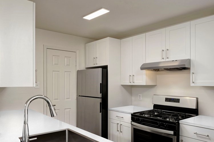 Renovated I kitchen with white cabinetry, white quartz countertops, stainless steel appliances, and hard surface flooring