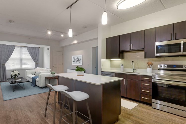 Renovated Package I apartment home with upgraded light quartz countertops, espresso cabinetry, stainless steel appliances, tile backsplash, and hard surface flooring throughout (in select homes)