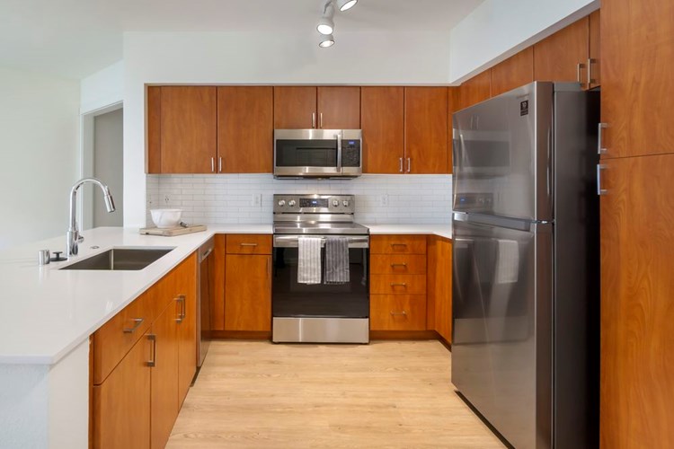 Newly renovated Finish Package II apartment homes feature kitchens with cherry cabinetry, white quartz countertops, stainless steel appliances, upgraded lightning, and hard surface flooring