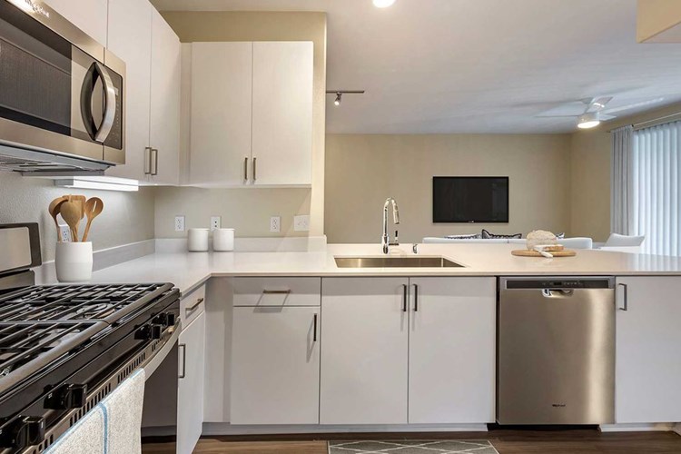 Renovated Package I kitchens with light grey quartz countertops, new white cabinetry, stainless steel appliances, upgraded fixtures, and hard surface flooring throughout