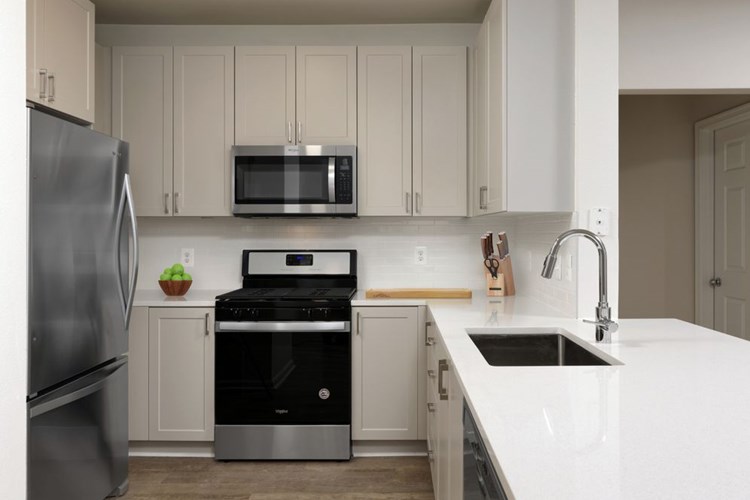 Renovated II kitchen with grey cabinetry, white quartz countertops, stainless steel appliances, white tile backsplash, and hard surface flooring
