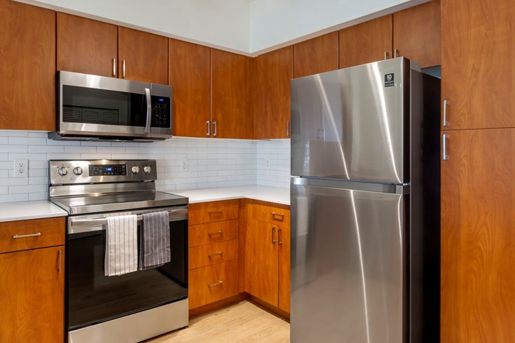Newly renovated Finish Package II apartment homes feature kitchens with cherry cabinetry, white quartz countertops, stainless steel appliances, upgraded lightning, and hard surface flooring