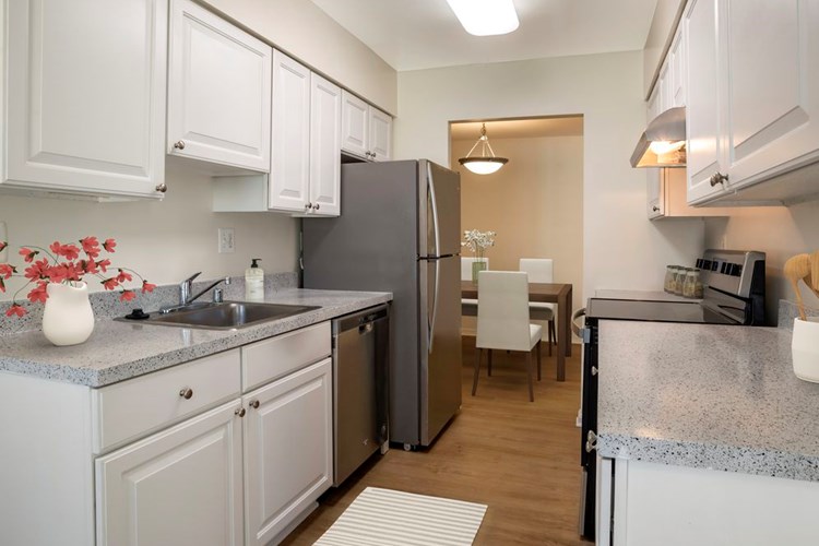 Renovated Package I kitchen featuring stainless steel appliances, white cabinetry, grey laminated countertops, and hard surface flooring