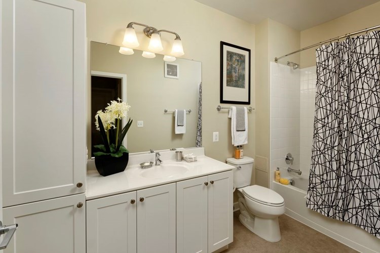 Bathroom with white shaker cabinetry, white countertop, shower and bath with white tile backsplash and hard surface flooring