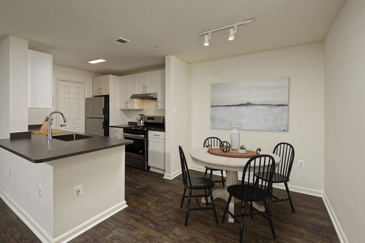 Renovated Package II kitchen and dining area with white cabinetry, dark grey laminate countertops, and stainless steel appliances, and hard surface plank flooring
