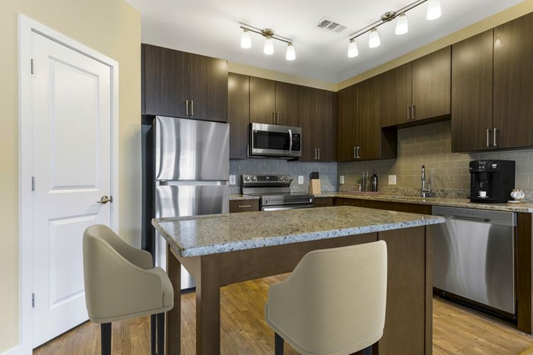 Upgraded kitchen with espresso cabinetry, grey speckled granite countertops, light grey tile backsplash, stainless steel appliances, and hard surface flooring