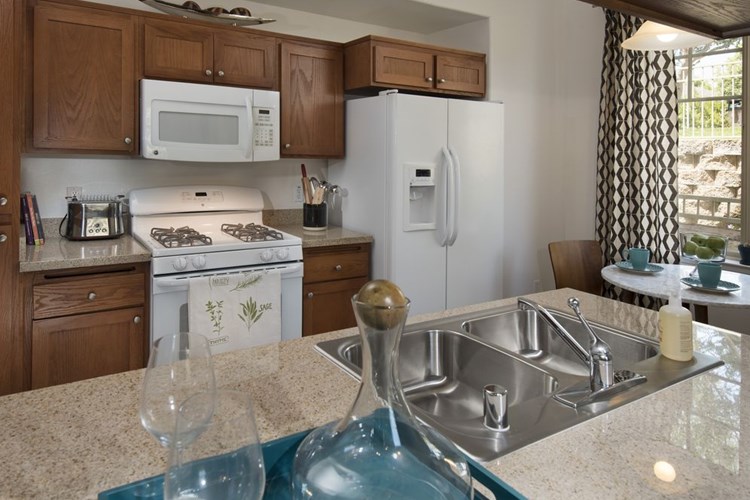 Classic Package I kitchen with maple cabinetry, beige speckled granite countertops, white appliances, and tile flooring