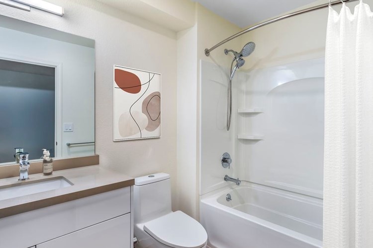 Renovated Package II bath with beige quartz countertops, white cabinetry, and hard surface flooring
