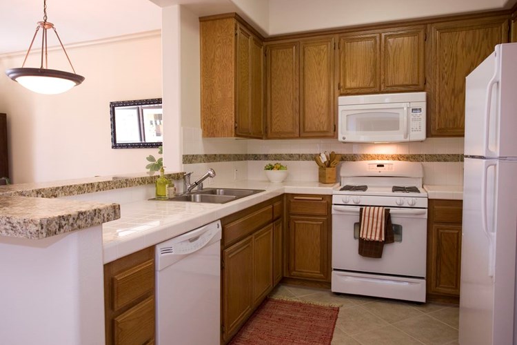 Classic Package I kitchen with white appliances, white tile countertop, oak cabinetry, and tile flooring