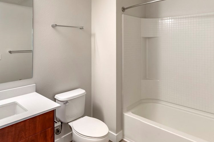 Renovated Package I bath with maple cabinetry, white quartz countertop, and hard surface flooring
