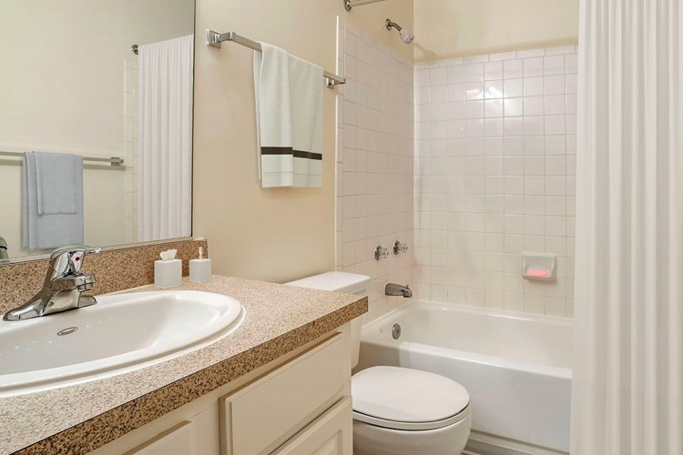 Classic Package bathroom with laminate countertop, white cabinetry and tile flooring