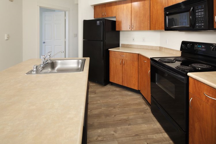 Classic Package I kitchen with laminate countertops, oak cabinetry, black appliances, and hard surface flooring