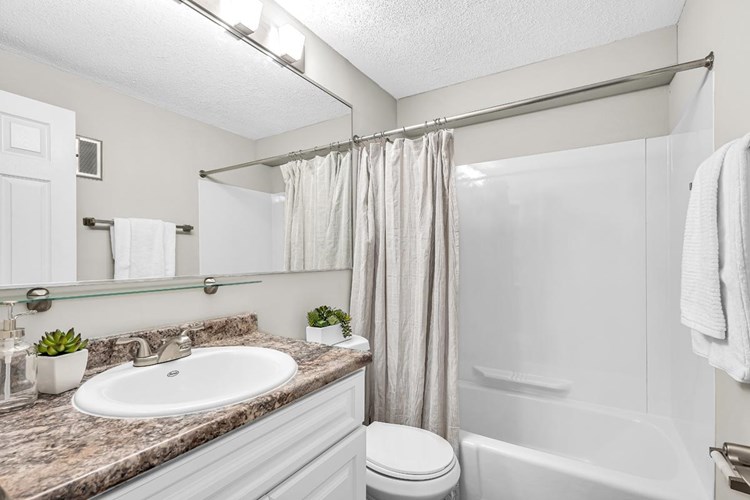 Updated bathrooms featuring granite-style counters and large mirrors.