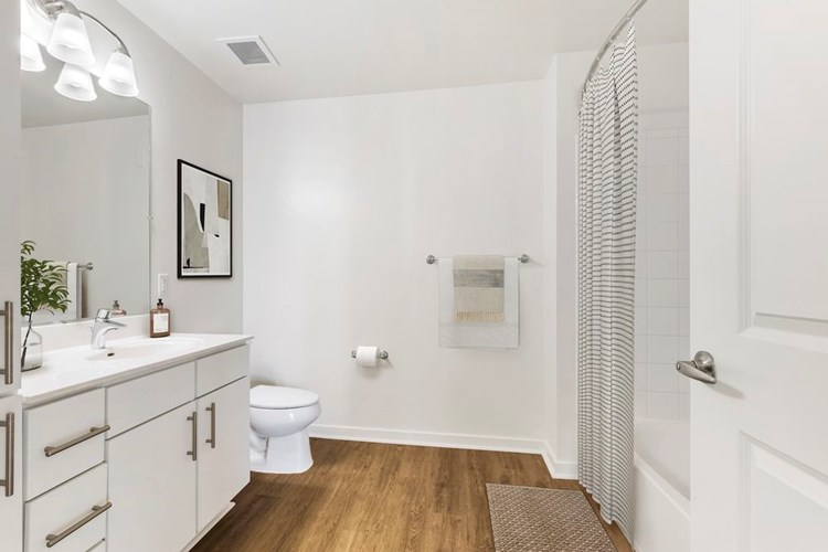 Renovated Package I bath with white laminate countertops, white cabinetry, and hard surface flooring
