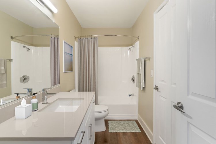 Renovated Package I bath with beige granite countertops, white cabinetry, and hard surface flooring