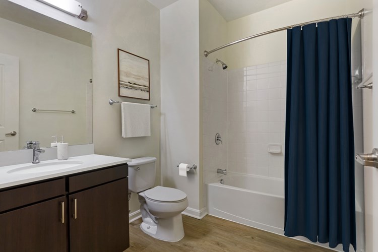 Renovated Package I bath with white quartz countertop, espresso cabinetry, and hard surface flooring