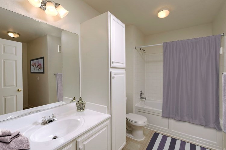 Classic Package bath white white cabinetry, white laminate countertops, and vinyl tile flooring