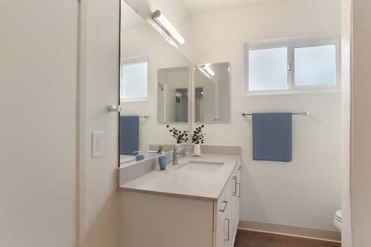 Renovated Package I bath with white cabinetry, beige granite countertops, and hard surface flooring