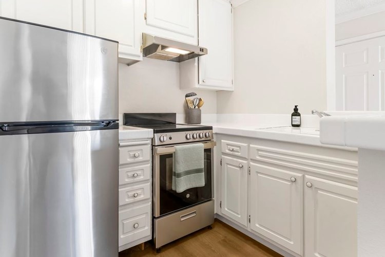 Classic Package II kitchen with stainless steel appliances, white tile countertops, white cabinetry, and hard surface flooring