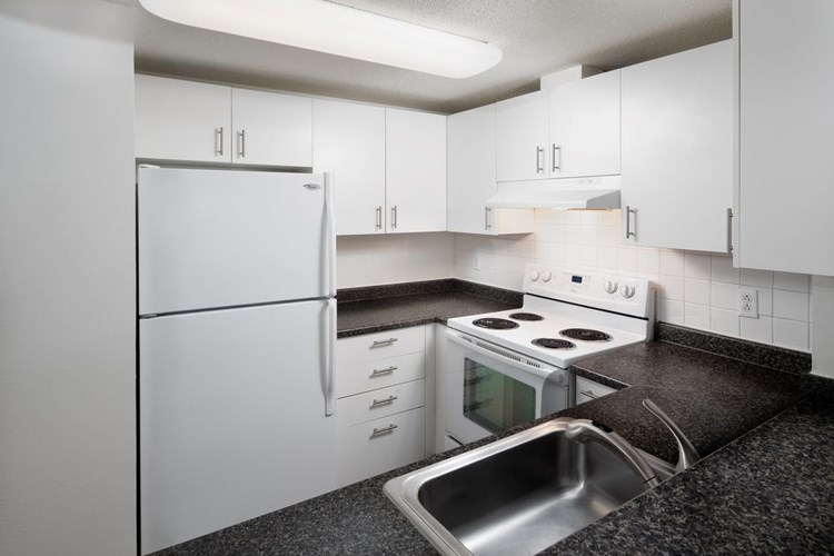 Classic Package I kitchen with white cabinetry, white tile backsplash, dark grey laminate countertops, white appliances, and hard surface flooring