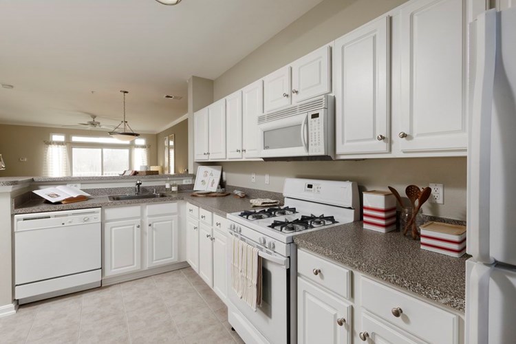Classic Package I kitchen with white appliances, white cabinetry, laminate countertops, and vinyl tile flooring
