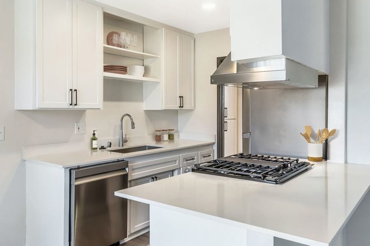 Renovated Package I kitchen with stainless steel appliances, white quartz countertops, white cabinetry, and hard surface flooring