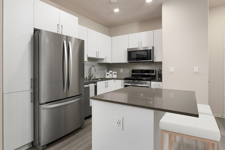 Renovated Package I kitchen with quartz countertops, white cabinetry, stainless steel appliances, hard surface vinyl plank flooring, and tile backsplash