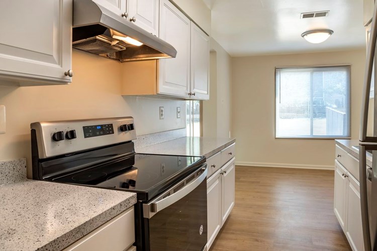 Renovated Package I kitchen featuring stainless steel appliances, white cabinetry, grey laminated countertops, and hard surface flooring