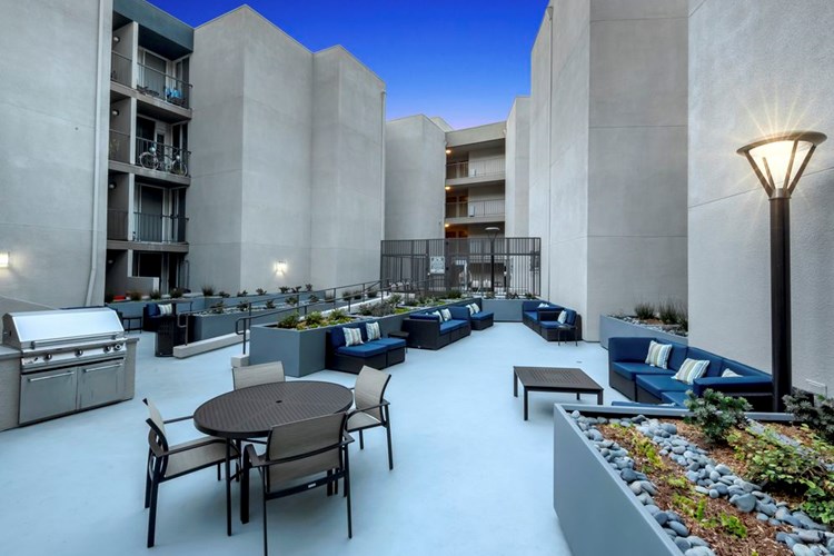 Resident courtyard with barbecue grills, fire pits, and lounge seating at dusk