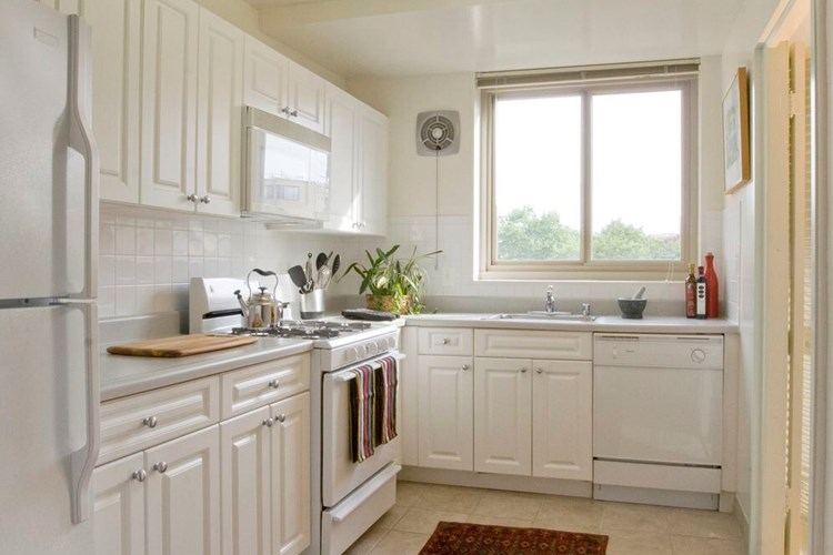 Kitchen with white cabinetry, white countertops, white appliances, tile backsplash and tile flooring